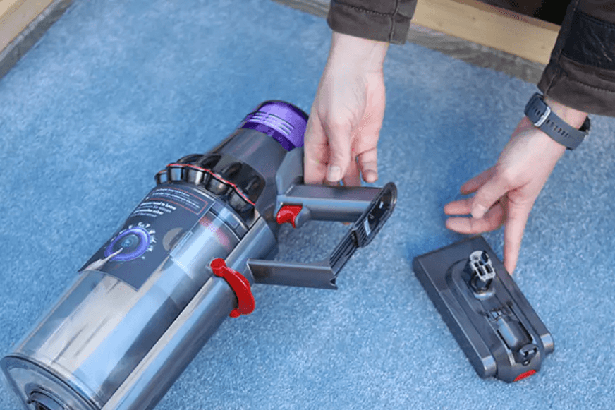 Der Akku eines Dyson Akkustaubsaugers liegt auf dem Teppich